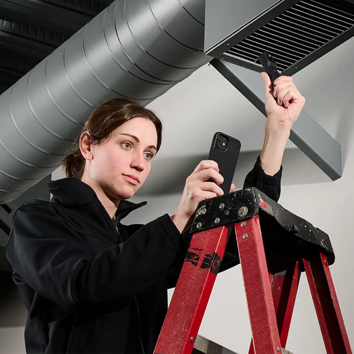 Teledyne Flir One Edge Compact Thermal Camera woman using device on ladder inspecting duct.